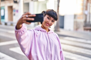 Young woman smiling confident making selfie by the smartphone at street