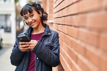 Young beautiful hispanic woman smiling confident using smartphone at street