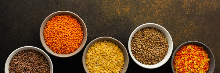 Multicolored lentils in bowls banner, yellow and brown, green and orange lentils, healthy legumes, top view, copy space