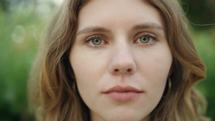 Young blonde woman standing with serious expression at park