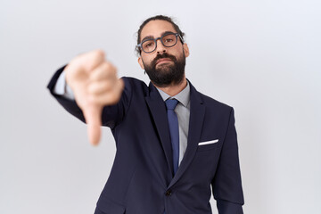 Hispanic man with beard wearing suit and tie looking unhappy and angry showing rejection and negative with thumbs down gesture. bad expression.