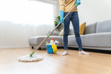 happy Female housekeeper service worker mopping living room floor by mop and cleaner product to...