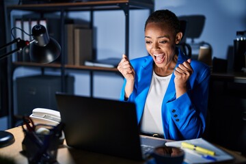 Beautiful african american woman working at the office at night celebrating surprised and amazed for success with arms raised and open eyes. winner concept.