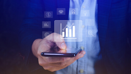 Data analytics and business intelligence BI concept with chart and graph icons on digital screen interface on smartphone and business people in the background.