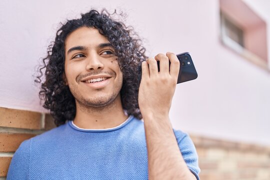 Young latin man smiling confident listening audio message by the smartphone at street