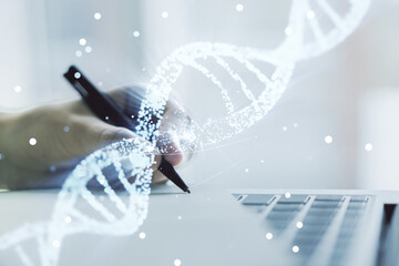 Creative light DNA illustration and hand writing in diary on background with laptop, science and...