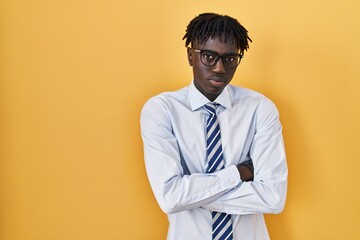 African man with dreadlocks standing over yellow background skeptic and nervous, disapproving...