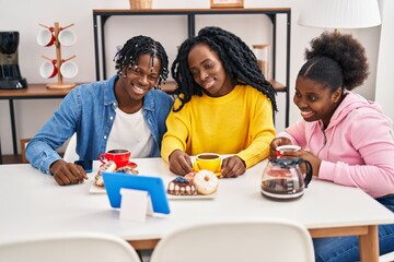 African american friends having breakfast watching video on touchpad at home