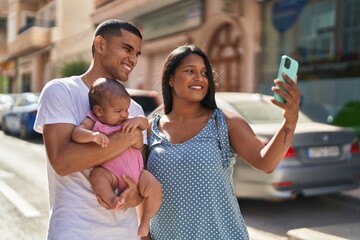 Hispanic family hugging each other making selfie by smartphone at street