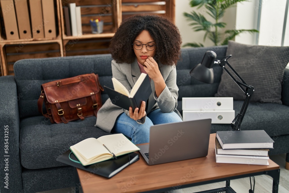 Poster Young african american woman psychologist using laptop and reading book at psychology center