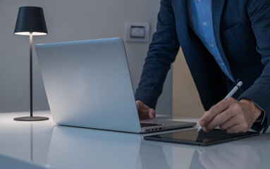 Businessman working with laptop and tablet sitting at the desk. Man write with electronic stylus pen