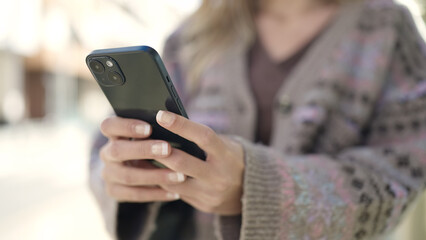 Young blonde woman using smartphone at street