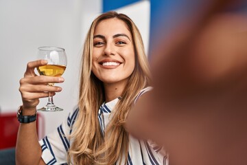 Young blonde woman make selfie by the smartphone drinking champagne at home