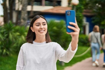 Young hispanic woman smiling confident making selfie by the smartphone at park