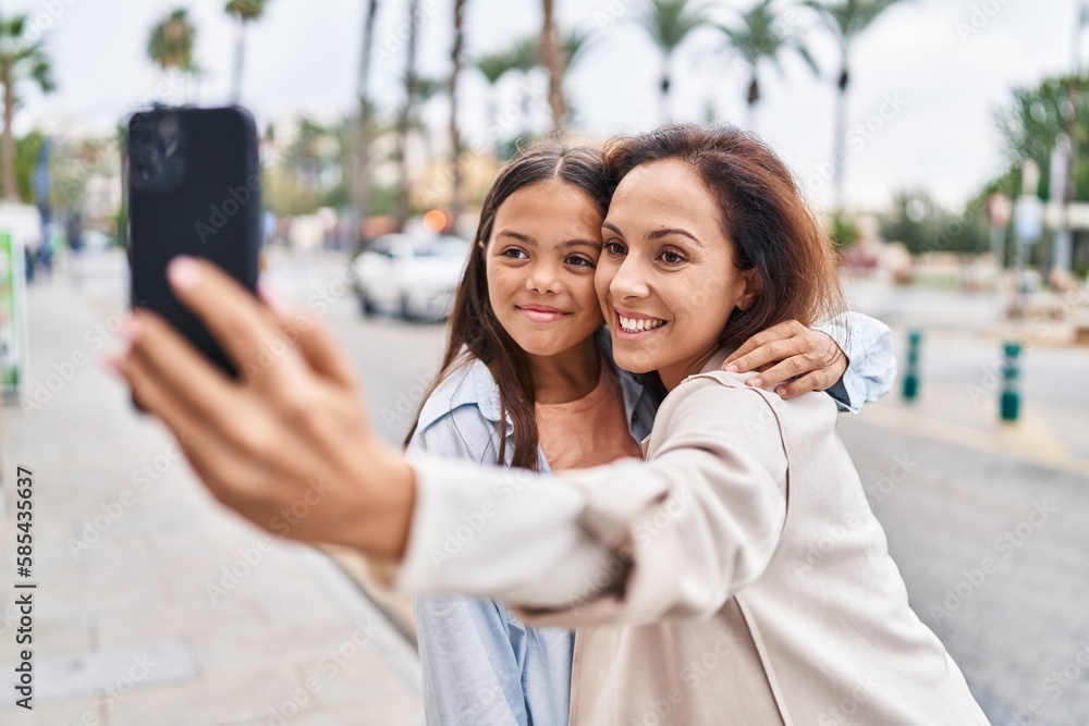 Wall mural Woman and girl mother and daughter making selfie by the smartphone at street