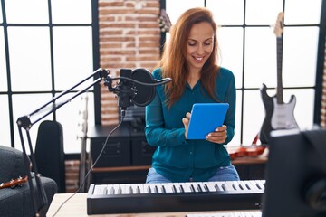 Young woman artist using touchpad at music studio