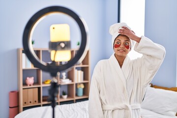 Hispanic woman with dark hair recording beauty tutorial with smartphone at home stressed and...