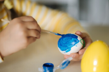 Macro photo of little girl growing easter eggs on kitchen. Yellow and blue colour. Ukrainian symbolic 