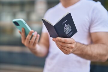 Young caucasian man using smartphone holding passport at street
