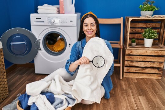Hispanic woman holding magnifying glass looking for stain at clothes smiling with a happy and cool smile on face. showing teeth.