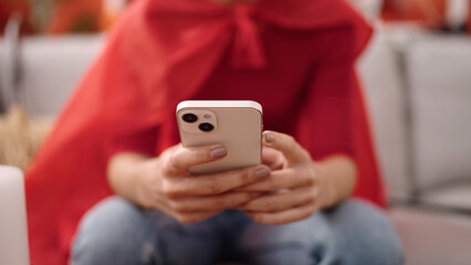 Young beautiful hispanic woman wearing devil costume using smartphone at home
