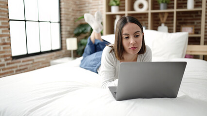 Young beautiful hispanic woman using laptop lying on bed at bedroom