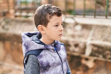 Blond child with relaxed expression standing at street