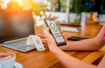 Woman using contactless payment by mobile phone with QR code at cafe