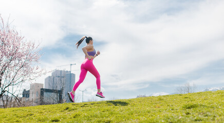 Woman running on hill for fitness as a sport in front of city
