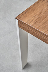 Minimalism style dining table with thin wooden table top of toned oak veneer on white metal legs closeup