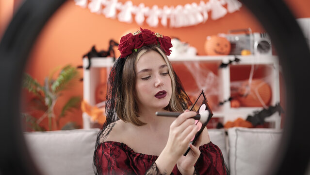 Young blonde woman wearing katrina costume recording makeup video at home