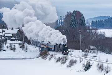 Retro steam train moves at winter morning.