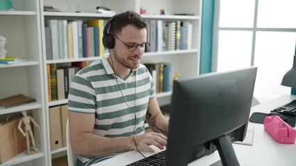 Young caucasian man using computer wearing headphones at library university