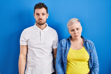 Fototapeta premium Young brazilian mother and son standing over blue background depressed and worry for distress, crying angry and afraid. sad expression.