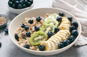 Oatmeal Bowl with Blueberry, Banana and Kiwi, Oat Porridge in a Bowl on Bright Background, Healthy Snack or Breakfast