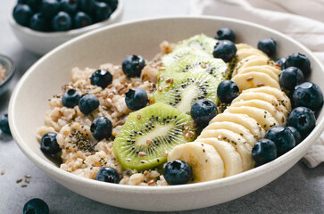 Oatmeal Bowl with Blueberry, Banana and Kiwi, Oat Porridge in a Bowl on Bright Background, Healthy Snack or Breakfast