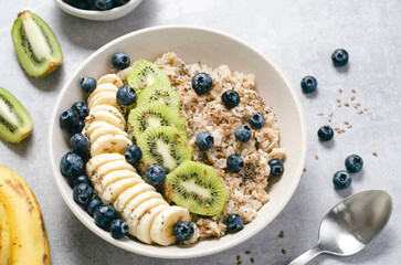 Oatmeal Bowl with Blueberry, Banana and Kiwi, Oat Porridge in a Bowl on Bright Background, Healthy Snack or Breakfast