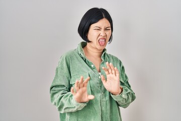 Young asian woman standing over white background disgusted expression, displeased and fearful doing...