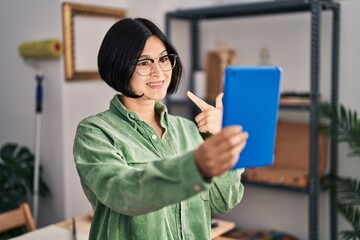 Young asian woman doing video call with tablet smiling happy pointing with hand and finger