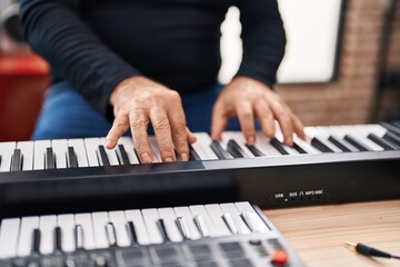 Obraz premium Middle age grey-haired man musician playing piano at music studio