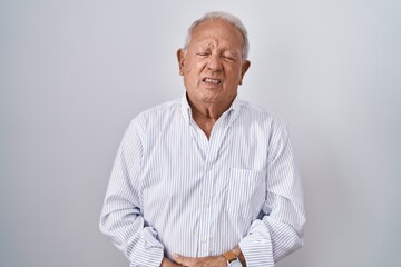 Senior man with grey hair standing over isolated background with hand on stomach because indigestion, painful illness feeling unwell. ache concept.