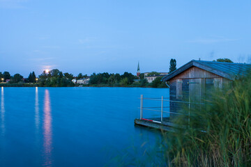 Zehdenick lake with houses at night illuminated with full moon in Brandenburg, Germany