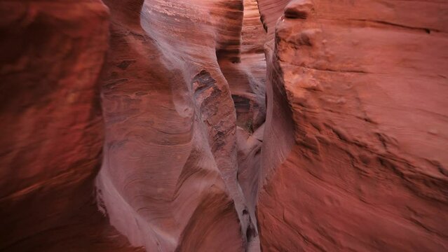 Hiker motion forward along narrow slot canyon with smooth red orange sandstone rocks in dried riverbed . Wavy walls of cave formed by erosion. Antelope Canyon is popular place for photos and travel
