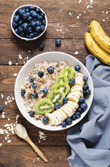 Oatmeal Bowl with Blueberry, Banana and Kiwi, Oat Porridge in a Bowl on Rustic Background, Healthy Snack or Breakfast