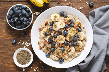 Oatmeal Bowl, Oat Porridge with Blueberry, Banana and Pecans in a Bowl on Wooden Background, Healthy Snack or Breakfast