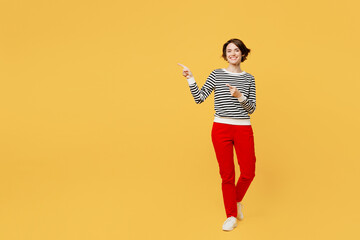 Fototapeta na wymiar Full body smiling young woman wear casual black and white shirt pointing finger aside indicate on workspace area copy space mock up isolated on plain yellow color background studio. Lifestyle concept.