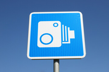Low angle view of  a Finnish road sign with a symbol for automatic traffic surveillance camera against clear blue sky.