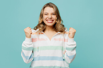 Young overjoyed happy caucasian blonde woman wear hoody doing winner gesture celebrate clenching...