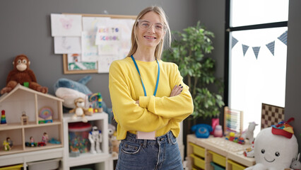 Young blonde woman working as teacher smiling happy at kindergarten