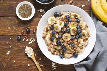 Oatmeal Bowl, Oat Porridge with Blueberry, Banana and Pecans in a Bowl on Wooden Background, Healthy Snack or Breakfast